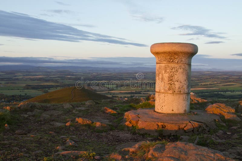 Plinth atop a hill. A stone plinth at the top of a hill in Scotland with golden light at dawn royalty free stock photography