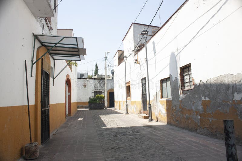 Stoned streets of Mexico City in a rustic town of the Assumption with the typical white walls painted with yellow in the. Lonely alley in the picturesque rustic royalty free stock images