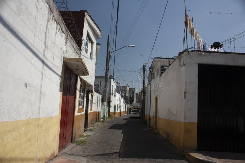 Streets of a picturesque rustic cobbled avenues village surrounding the exterior facades painted bicolor in yellow and white Mexic. Cobblestone alley in Mexico royalty free stock image