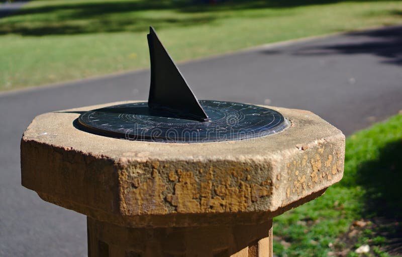 Sun dial mounted on a stone plinth. Close up view of black color sun dial mounted on a stone plinth stock photos