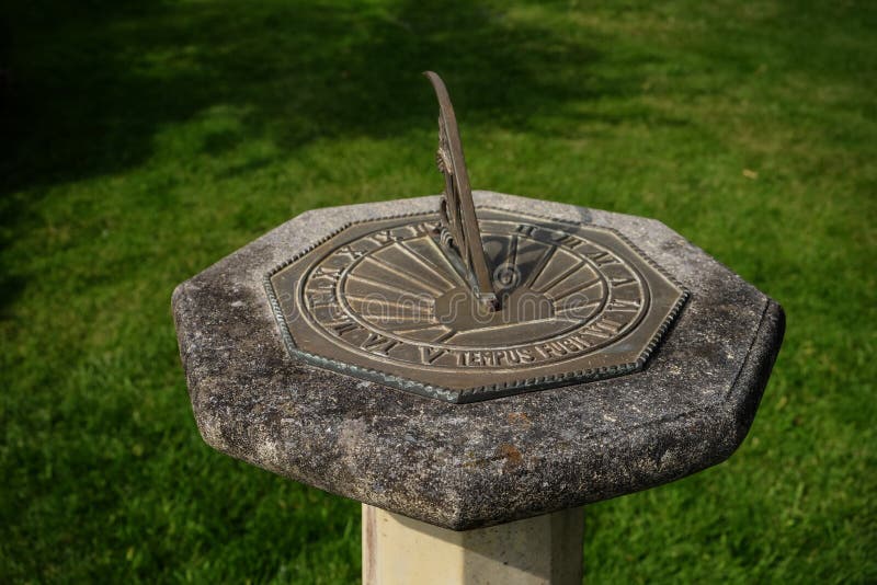 Sundial on stone plinth with inscription `tempus fugi` latin for time flies. Sundial on stone plinth with inscription `tempus fugit` latin for time flies in stock image