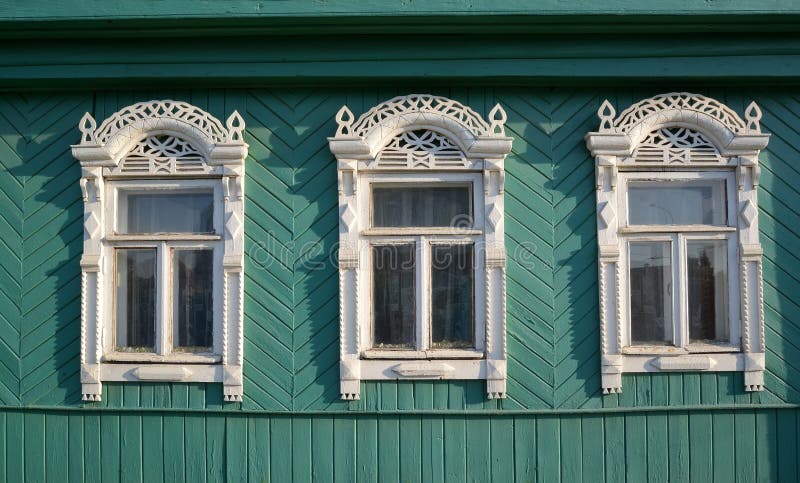 Three windows with white carved platbands stock image