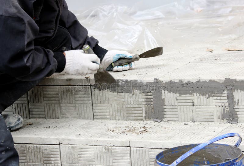 tiler glosses over gaps between the stacked stone tiles on the steps in the repair of the office building stock images