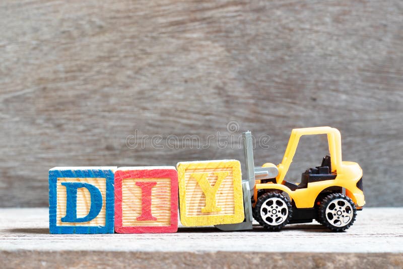Toy forklift hold letter block Y to word DIY abbreviation of do it yourself on wood background stock image