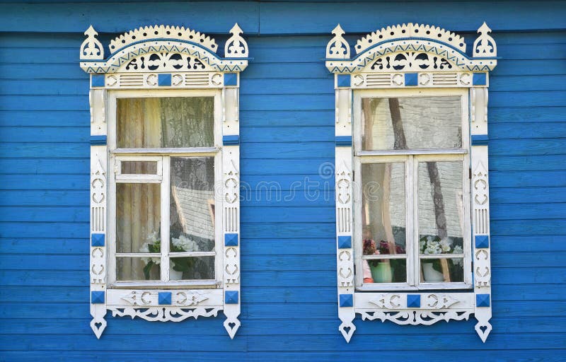 Two windows with carved platbands on the blue wooden house royalty free stock image