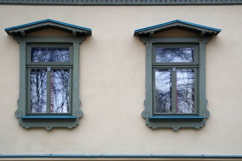 Two windows in an old house in a city park. Beautiful platbands and reflection in glasses. stock images