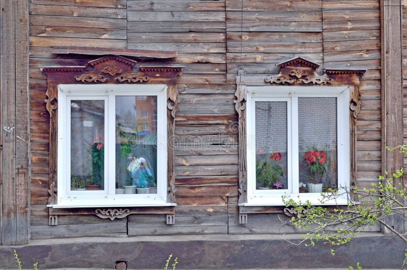 Two windows in an old wooden house decorated with wooden carving stock photo