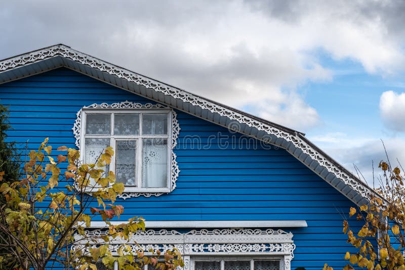 White carved platbands on the windows and the ridge of the roof of a blue house royalty free stock photography