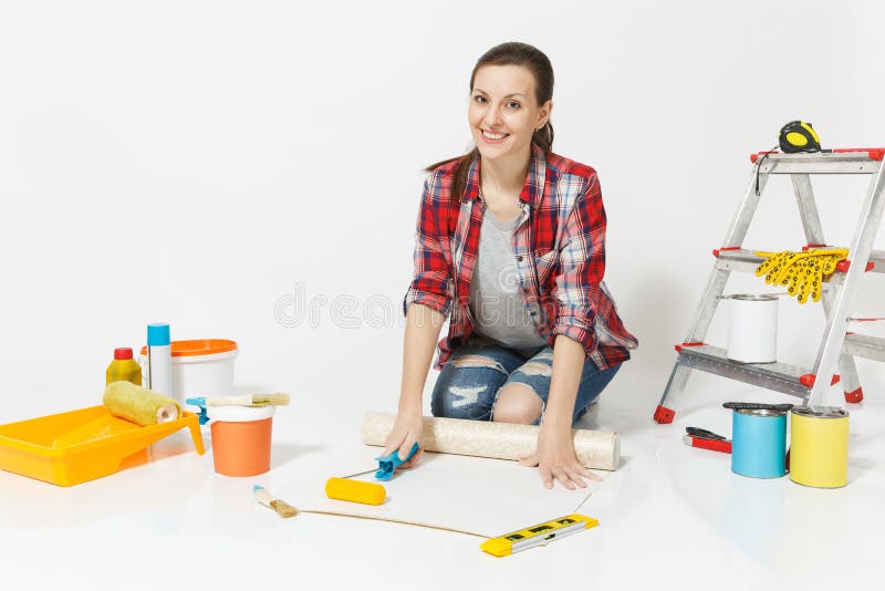Woman in casual clothes sitting on floor with wallpaper rolls, paint roller, instruments for renovation apartment. Isolated on white background. Accessories for royalty free stock images