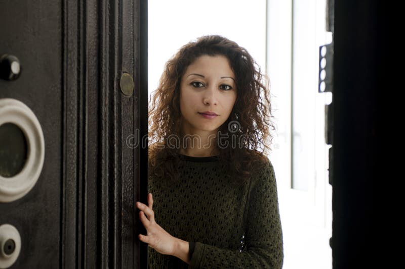 Woman opening the front door. Latin woman opening the front door, white inside stock photography