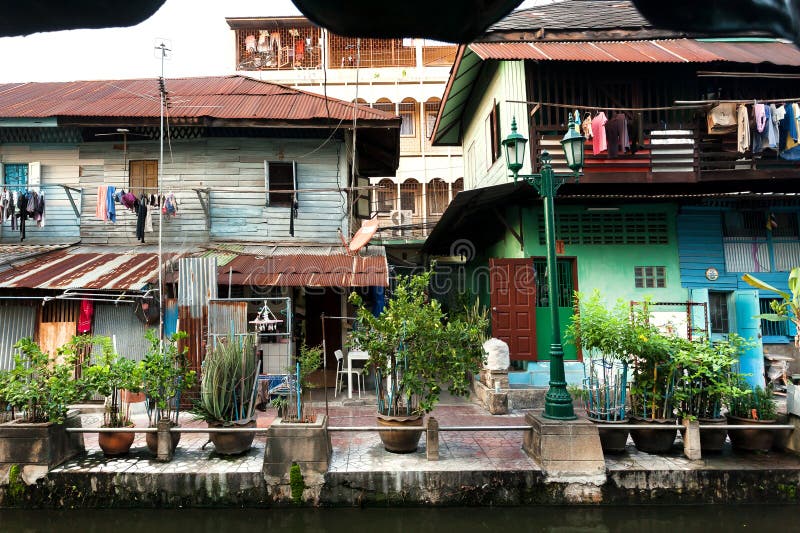 Wooden facades of old rustic houses on riverbanks of Bangkok. Vintage homes and plants on narrow street in Thailand.  stock photo