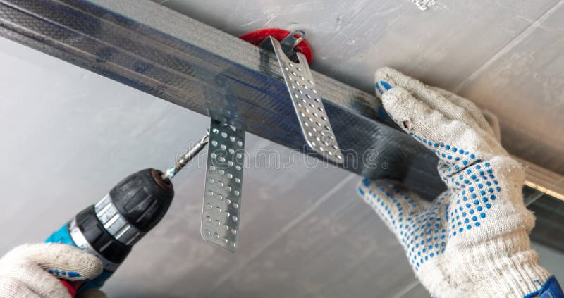 Worker fastens a metal profile to the ceiling. Repair of a room in the house royalty free stock photography