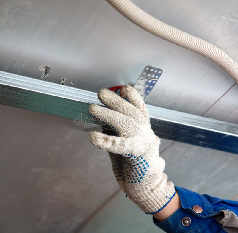 Worker fastens a metal profile to the ceiling. Repair of a room in the house stock images