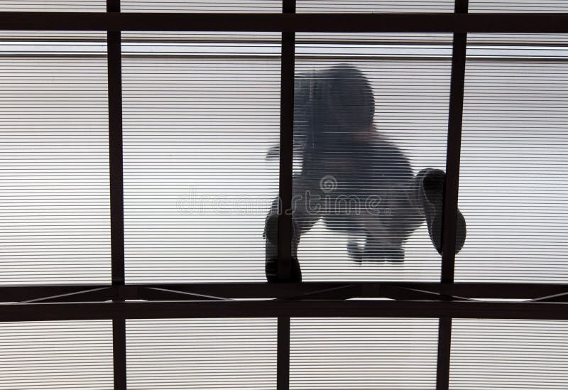 A worker mounts a metal canopy in the courtyard of the house. Silhouette man bottom view stock image