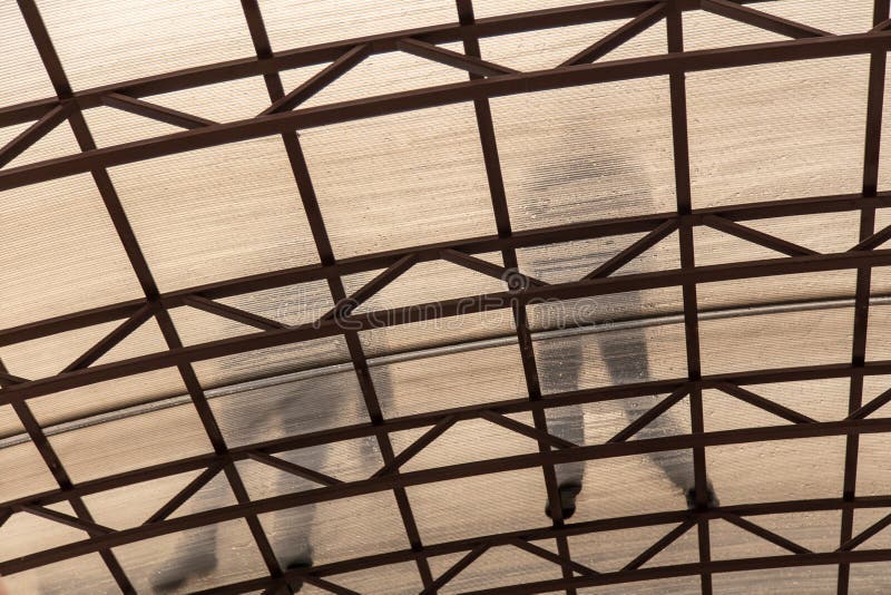 A worker mounts a metal canopy in the courtyard of the house. Silhouette man bottom view stock photos