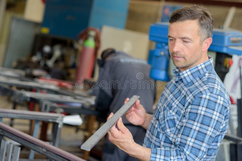 Workman holding length of metal. And examining it stock photos
