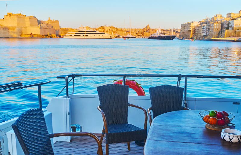On yacht`s board in Valletta Grand Harbour, Malt. Relax on yacht`s board with a view on Fort St Angelo of Birgu and luxury ships in Vittoriosa marina, Valletta stock photos
