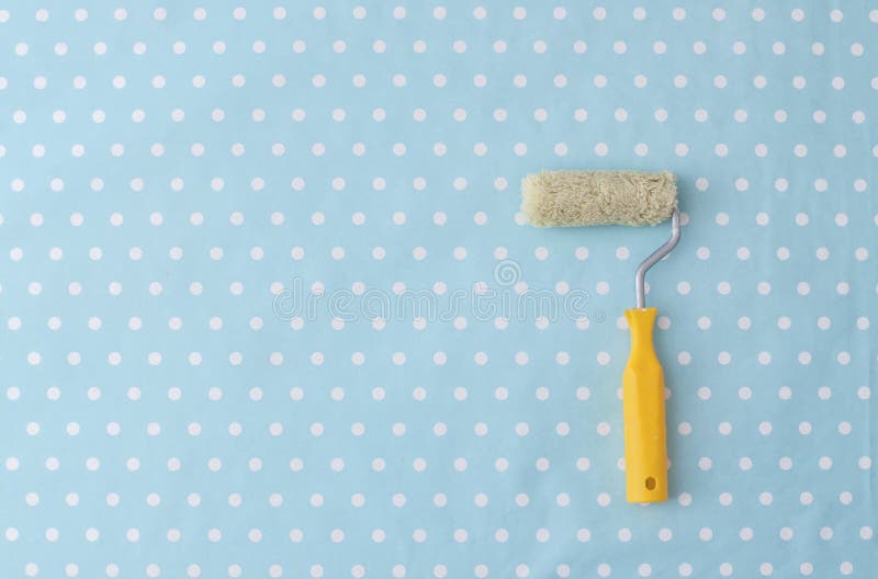 Yellow paint roller over blue polka dot wallpaper. In nursery room royalty free stock photography